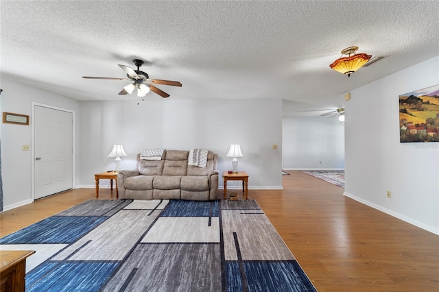 living room featuring ceiling fan, wood-type flooring, and a textured ceiling