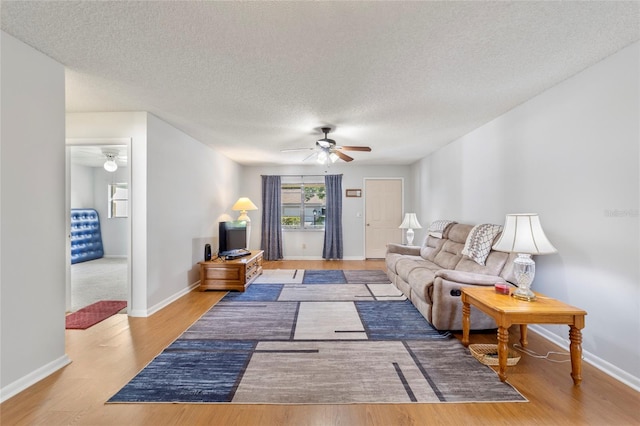 living room featuring a textured ceiling, light hardwood / wood-style floors, and ceiling fan