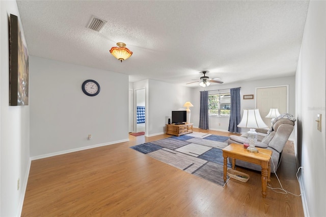 living room featuring a textured ceiling, hardwood / wood-style flooring, and ceiling fan