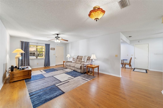 living room featuring ceiling fan, light hardwood / wood-style floors, and a textured ceiling