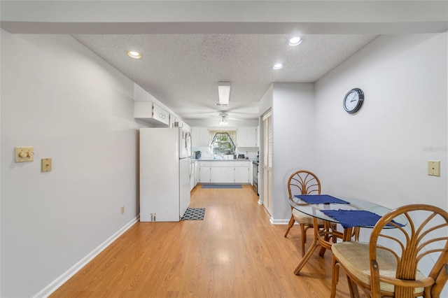 kitchen featuring light hardwood / wood-style floors, a textured ceiling, ceiling fan, white fridge, and white cabinetry