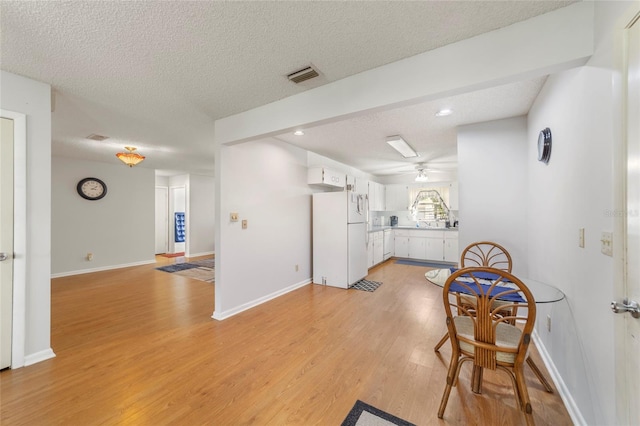 kitchen with ceiling fan, light hardwood / wood-style flooring, white refrigerator, a textured ceiling, and white cabinets