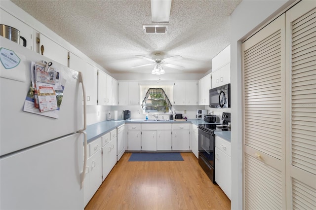 kitchen featuring white cabinets, a textured ceiling, light hardwood / wood-style floors, and black appliances