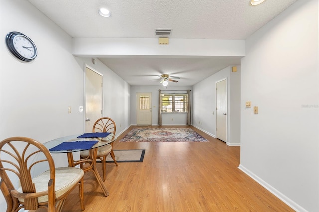 doorway with ceiling fan, light wood-type flooring, and a textured ceiling