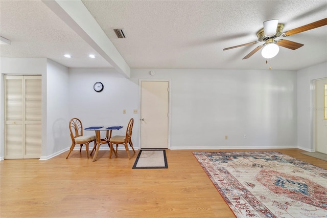 interior space featuring ceiling fan, light hardwood / wood-style floors, and a textured ceiling