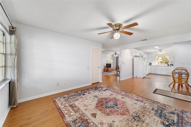 dining area featuring ceiling fan, light wood-type flooring, and a textured ceiling