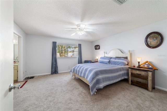 carpeted bedroom featuring ceiling fan, ensuite bathroom, and a textured ceiling