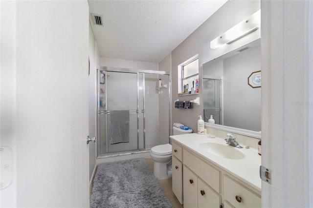 bathroom with a textured ceiling, vanity, toilet, and an enclosed shower