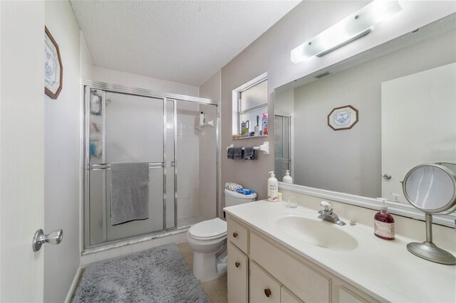 bathroom featuring tile patterned flooring, vanity, a textured ceiling, and an enclosed shower