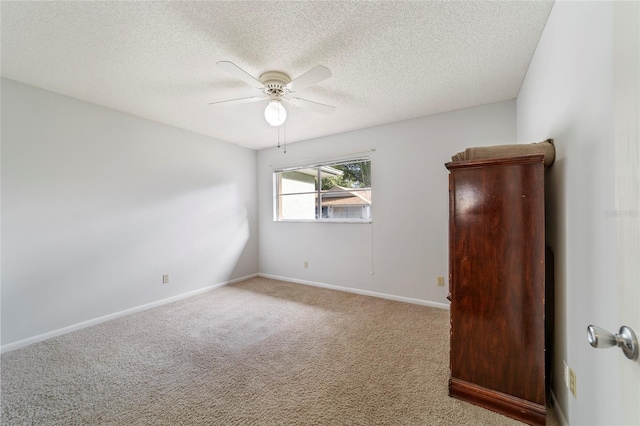 carpeted empty room with ceiling fan and a textured ceiling