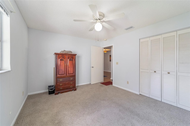 unfurnished bedroom with light carpet, a textured ceiling, a closet, and ceiling fan