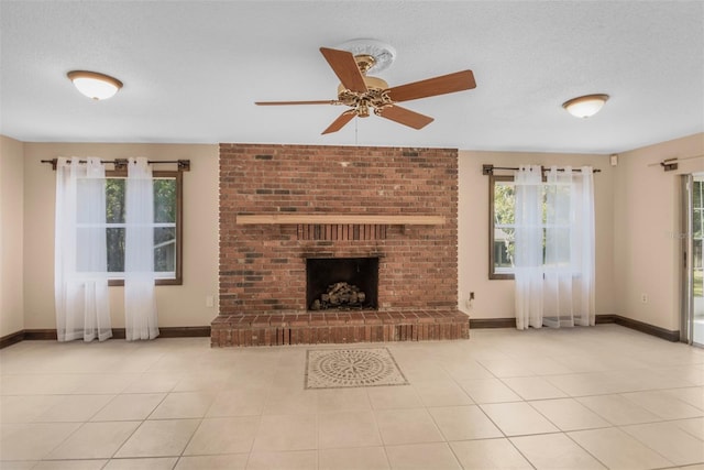 unfurnished living room featuring ceiling fan, light tile patterned floors, a textured ceiling, and a brick fireplace