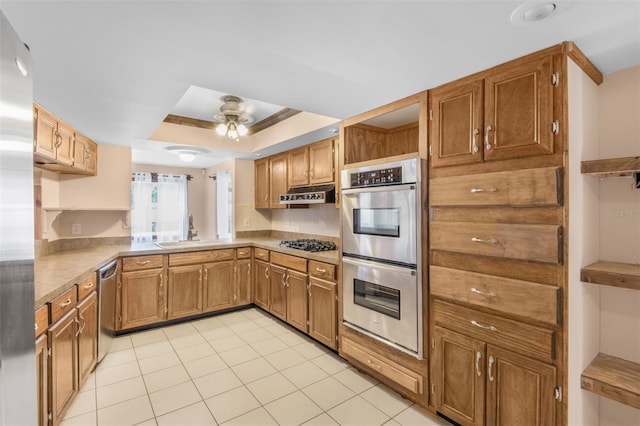 kitchen featuring ceiling fan, sink, a raised ceiling, light tile patterned floors, and appliances with stainless steel finishes