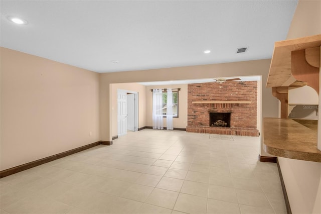 unfurnished living room featuring ceiling fan, light tile patterned flooring, and a brick fireplace