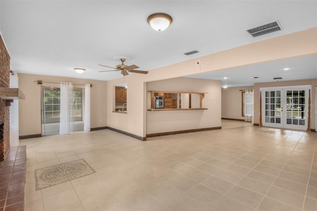 unfurnished living room with ceiling fan, french doors, sink, a fireplace, and light tile patterned floors