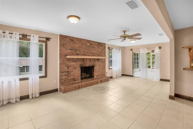 unfurnished living room featuring ceiling fan, light tile patterned flooring, and a brick fireplace