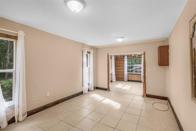 tiled empty room with a textured ceiling and a wealth of natural light