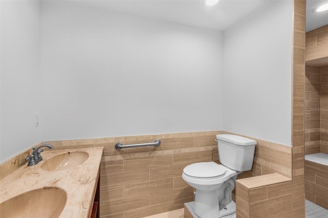 bathroom featuring tile patterned floors, vanity, toilet, and tile walls