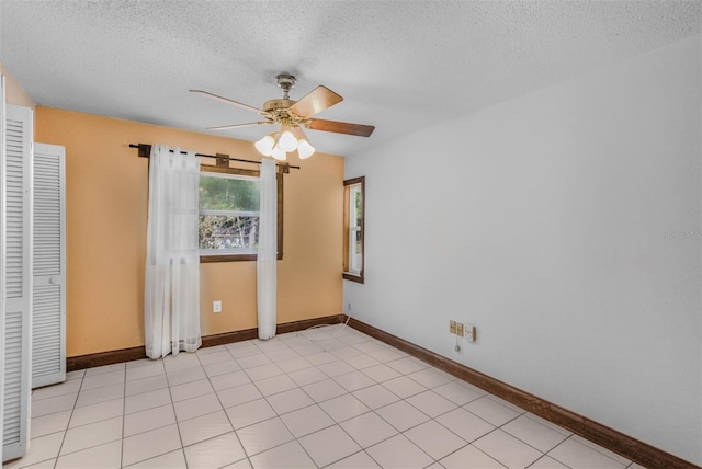 spare room with light tile patterned floors, a textured ceiling, and ceiling fan