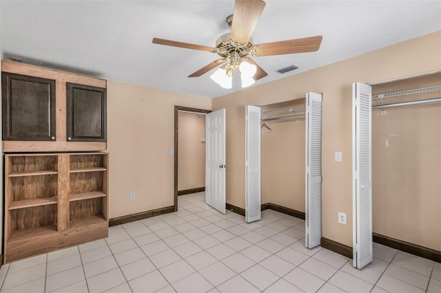 unfurnished bedroom with ceiling fan, light tile patterned flooring, and a textured ceiling