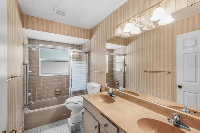 full bathroom featuring tile patterned flooring, vanity, toilet, and tiled shower / bath combo