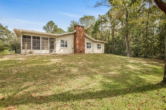 back of property featuring a lawn and a sunroom