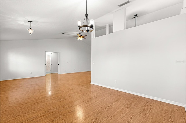 spare room with ceiling fan with notable chandelier, lofted ceiling, and light hardwood / wood-style flooring