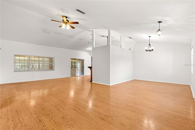 unfurnished living room with ceiling fan with notable chandelier, light wood-type flooring, and lofted ceiling