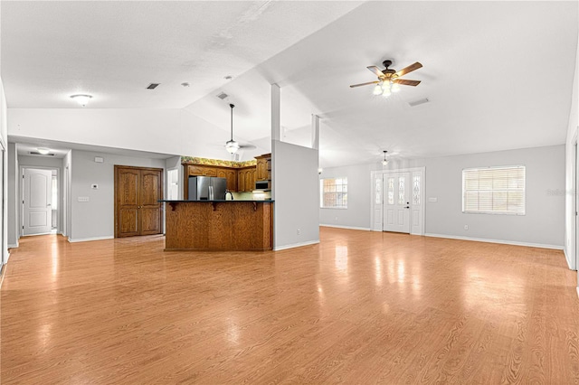 unfurnished living room with ceiling fan, vaulted ceiling, and light wood-type flooring