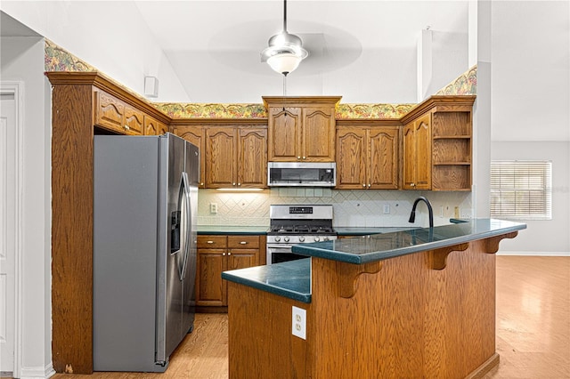 kitchen with backsplash, light wood-type flooring, a kitchen bar, kitchen peninsula, and stainless steel appliances