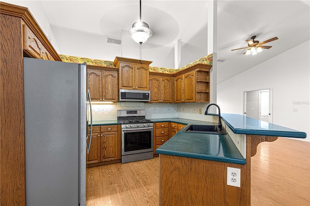 kitchen featuring lofted ceiling, sink, decorative backsplash, light hardwood / wood-style floors, and stainless steel appliances