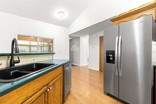 kitchen with light hardwood / wood-style floors, sink, appliances with stainless steel finishes, and vaulted ceiling