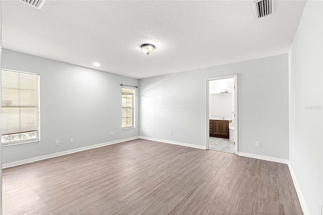 unfurnished room with a textured ceiling and light hardwood / wood-style flooring