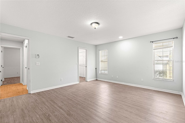 empty room with hardwood / wood-style floors and a textured ceiling