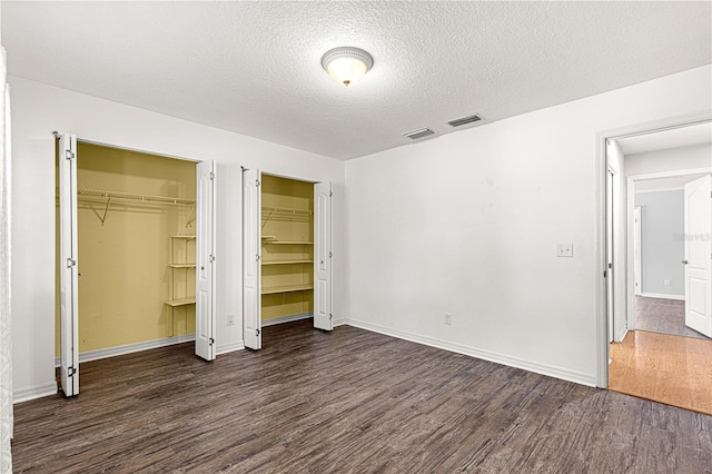 unfurnished bedroom with a textured ceiling and dark wood-type flooring