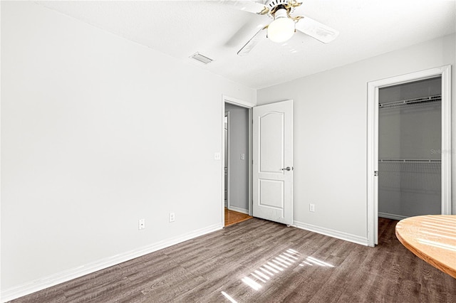 unfurnished bedroom with hardwood / wood-style floors, ceiling fan, a walk in closet, and a closet