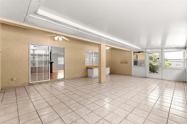 unfurnished sunroom featuring ceiling fan