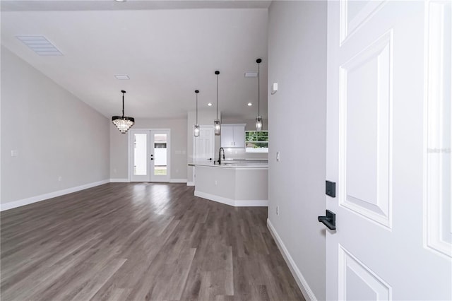 unfurnished living room featuring a wealth of natural light, sink, dark hardwood / wood-style floors, and a notable chandelier