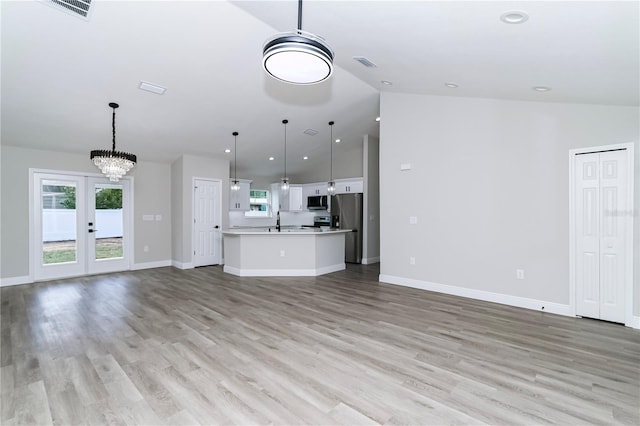 unfurnished living room with french doors, sink, a notable chandelier, vaulted ceiling, and light wood-type flooring