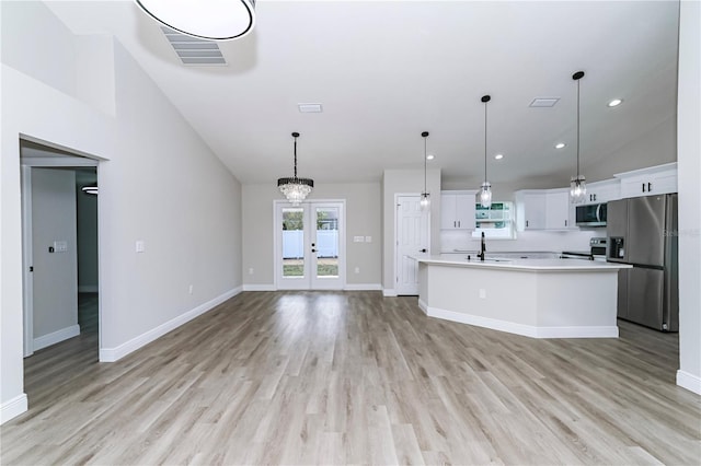 kitchen featuring stainless steel appliances, a center island with sink, light hardwood / wood-style floors, white cabinetry, and hanging light fixtures