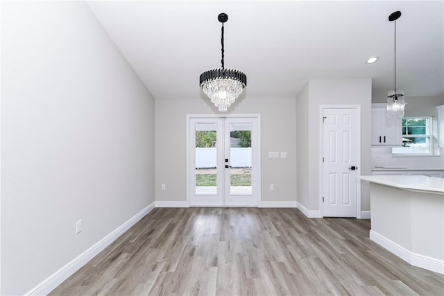 unfurnished dining area featuring french doors, light hardwood / wood-style floors, and a notable chandelier