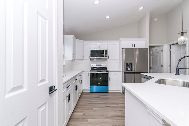 kitchen featuring appliances with stainless steel finishes, white cabinetry, vaulted ceiling, and sink