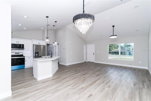 kitchen with a center island with sink, white cabinets, hanging light fixtures, light wood-type flooring, and appliances with stainless steel finishes