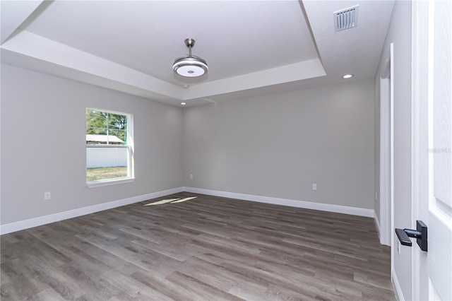 spare room featuring wood-type flooring and a tray ceiling