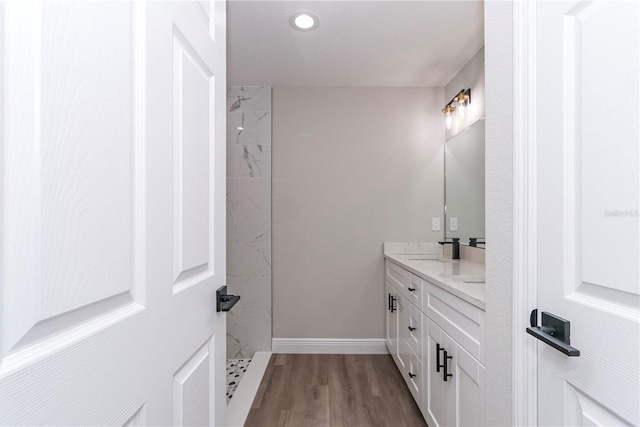 bathroom with vanity, wood-type flooring, and tiled shower