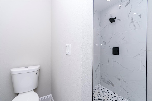 bathroom featuring tiled shower and toilet