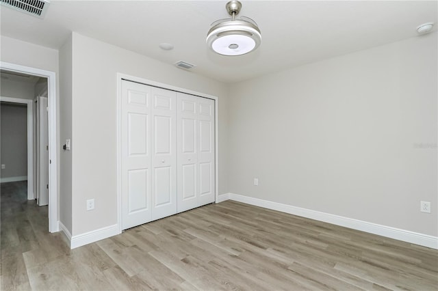 unfurnished bedroom with light wood-type flooring and a closet