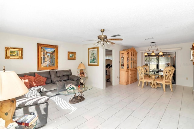 living room with ceiling fan, light tile patterned floors, and a textured ceiling