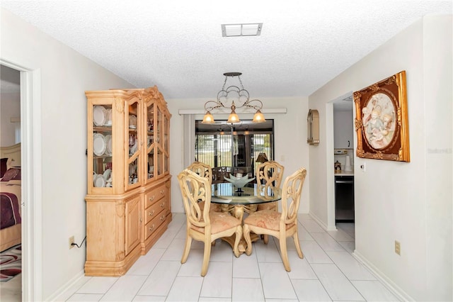 tiled dining space featuring a textured ceiling and an inviting chandelier