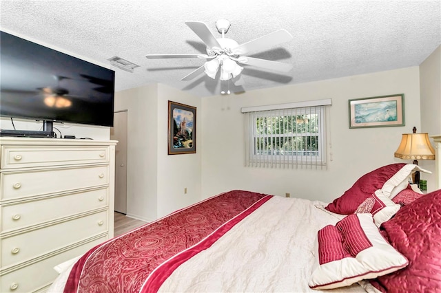 bedroom with ceiling fan, a textured ceiling, and light wood-type flooring